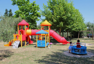 Kleurrijke speeltuin met glijbanen en kinderen spelend bij Camping Cisano/San Vito in Veneto, Italië.