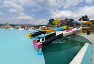 Vandland i Camping Cisano/San Vito, Veneto, Italien, med farverige vandrutsjebaner og pool under blå himmel.