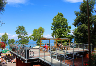 Udsigt over terrasse med cykler og siddepladser i ferieparken Camping Cisano/San Vito, Veneto, Italien.