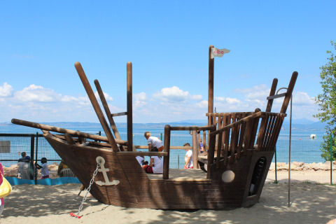 Houten piratenschip-speeltuig aan het strand van Camping Cisano/San Vito in Veneto, Italië.