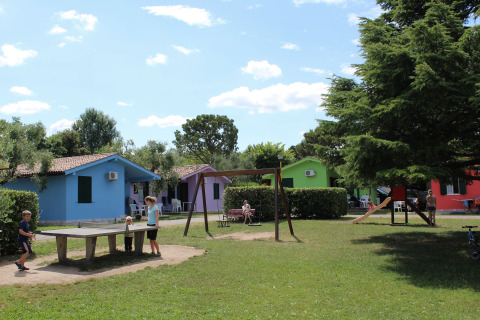 Colorful cabins, children playing table tennis and at a playground at Camping Cisano/San Vito holiday park, Italy.