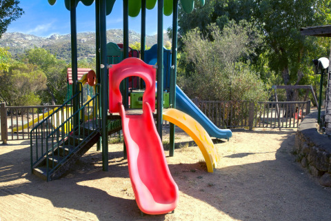 Parque infantil colorido con tobogán en Camping Gasparina en Véneto, Italia, rodeado de árboles.