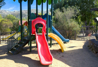 Colorful playground with slides at Camping Gasparina in Veneto, Italy, surrounded by trees and hills.
