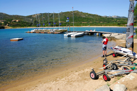 Persoon aan het strand bij een aanlegsteiger en zeilboten op Camping Gasparina, vakantiepark in Veneto, Italië.