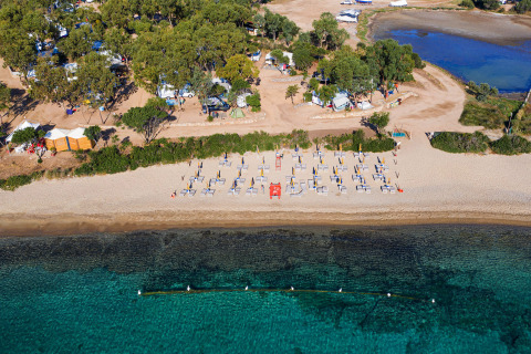 Aerial view of Camping Gasparina in Veneto, Italy, featuring a sandy beach, umbrellas, loungers and clear water.