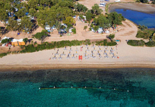 Aerial view of Camping Gasparina in Veneto, Italy, featuring a sandy beach, umbrellas, loungers and clear water.