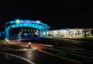 Entrance to Camping Pra’delle Torri holiday park in Veneto, Italy, illuminated with blue lights at night.
