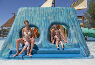 Famiglia che si diverte sullo scivolo blu a Camping Pra'delle Torri, parco vacanze a Veneto, Italia.