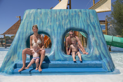 Gezin geniet van blauwe glijbaan op de waterspeelplaats van Camping Pra'delle Torri in Veneto, Italië.