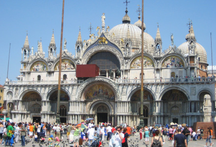 Turistas visitan la majestuosa Basílica de San Marcos en Venecia, famosa por sus cúpulas y mosaicos.