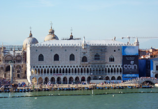 Udsigt over Dogepaladset i Venedig nær Caorle, Veneto, Italien, med folk ved kajen og kanalen foran.
