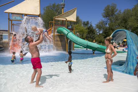Famiglie si divertono in una giornata di sole all’area giochi acquatica di Camping Pra’delle Torri in Veneto, Italia.