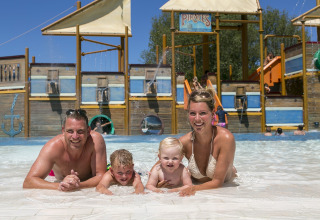 En familie nyder en solskinsdag ved swimmingpoolen på Camping Pra'delle Torri feriepark i Veneto, Italien.