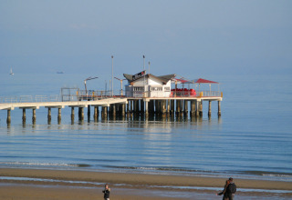 View of a pier with a restaurant on the sea at Camping Pra'delle Torri, Veneto, Italy, on a calm day.