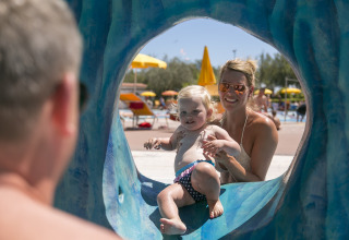 Mother and child having fun at the slide in Camping Pra'delle Torri holiday park, Veneto, Italy, sunny day.