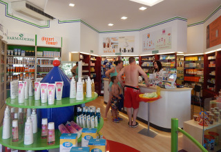 Familie winkelt in een apotheek met zonnecrème op Camping Pra'delle Torri in Veneto, Italië.