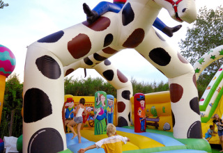 Bambini che giocano su un grande gonfiabile cowboy a cavallo al Camping Pra'delle Torri, Veneto, Italia.