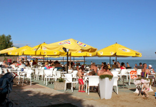 Bar all'aperto con ombrelloni gialli sulla spiaggia del Camping Pra'delle Torri, Veneto, Italia.
