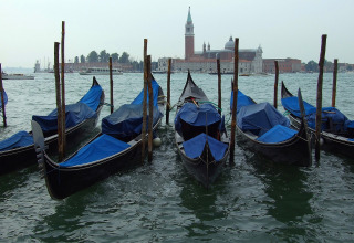 Gondolas moored with blue covers in Venetian waters, historic buildings in the background, Veneto, Italy.
