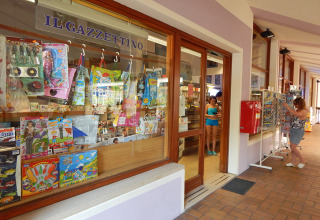 Shop window at Camping Pra'delle Torri in Veneto, Italy, displaying toys and magazines with people outside.