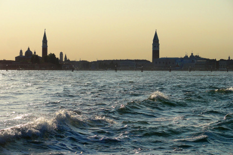 View across the water towards the iconic skyline near Camping Pra'delle Torri holiday park in Veneto, Italy at dusk.