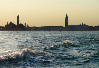 View across the water towards the iconic skyline near Camping Pra'delle Torri holiday park in Veneto, Italy at dusk.
