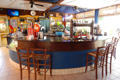 Zona de bar en el Camping Pra'delle Torri, parque vacacional en Véneto, Italia, con taburetes y bebidas.