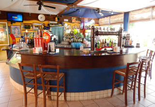 Area bar presso Camping Pra'delle Torri, villaggio turistico in Veneto, Italia, con sgabelli e bevande.