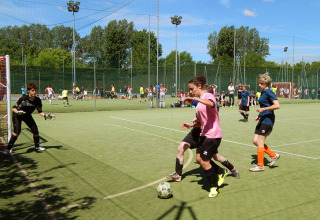 Jongvolwassenen spelen voetbal op het sportveld bij Camping Pra'delle Torri, vakantiepark in Veneto, Italië.