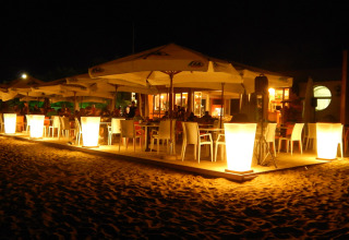 Outdoor dining area at Camping Pra'delle Torri, Veneto, Italy, brightly lit with large lamps at night.