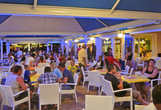 Udendørs restaurant ved Camping Pra'delle Torri, Veneto, Italien, fyldt med feriegæster om aftenen.