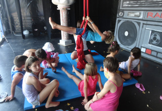 Bambini partecipano ad acrobazie e giochi aerei su tappetini al Camping Pra'delle Torri, Veneto, Italia.