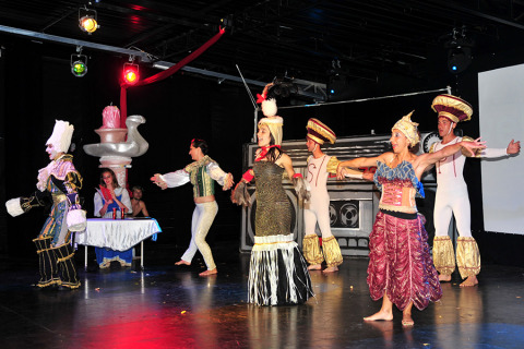 Performers in colorful costumes act on stage during a theatrical show at Camping Pra'delle Torri in Veneto, Italy.
