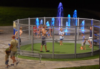 Børn leger fodbold i en indhegnet børnepark om aftenen ved Camping Pra'delle Torri, Veneto, Italien.