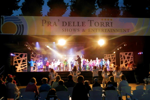 Espectáculo nocturno en el escenario al aire libre de Camping Pra'delle Torri en Véneto, Italia, con público.