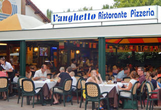 Outdoor diners at Vanghetto Ristorante Pizzeria at Camping Pra'delle Torri holiday park in Veneto, Italy.