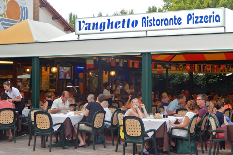 Comensales disfrutando al aire libre en Vanghetto Ristorante Pizzeria del Camping Pra'delle Torri en Véneto, Italia.