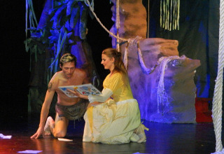 Two actors perform on stage at Camping Pra'delle Torri, Veneto, Italy, with a jungle set in the background.