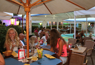 Outdoor restaurant scene at Camping Pra'delle Torri, Veneto, Italy, with guests relaxing and enjoying drinks.