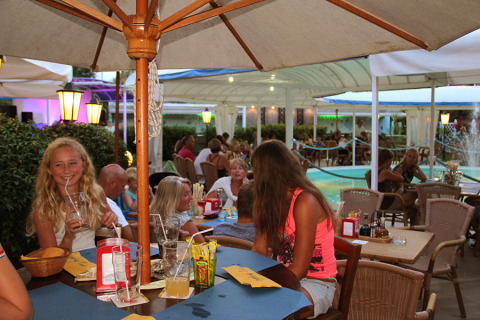 Terraza de restaurante en Camping Pra'delle Torri, Véneto, Italia, con huéspedes disfrutando el ambiente.