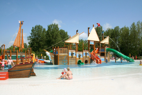 Children play on a large pirate ship water playground at Camping Pra'delle Torri, Veneto, Italy, on a sunny day.
