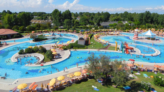 Vista aérea del parque acuático en Camping Pra'delle Torri con piscinas, toboganes y tumbonas.