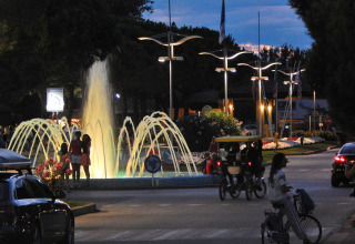 Personas disfrutan de la fuente iluminada por la noche en Camping Pra'delle Torri, Veneto, Italia.