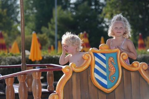 Due bambini giocano su un parco giochi con stemma a cavalluccio marino al Camping Pra'delle Torri, Veneto, Italia.