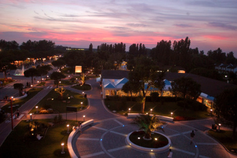 Vista serale al Camping Pra'delle Torri in Veneto, Italia, con sentieri illuminati e cielo al tramonto.