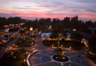 Evening view at Camping Pra'delle Torri in Veneto, Italy, showing lit pathways and a vibrant sunset sky.