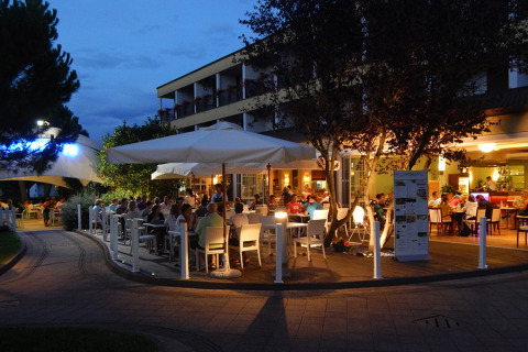 Zona de comedor al aire libre en Camping Pra'delle Torri en Véneto, Italia, ocupada por huéspedes al anochecer.