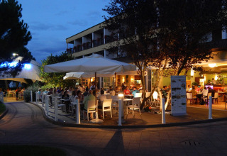 Udendørs restaurant på Camping Pra'delle Torri i Veneto, Italien, fyldt med gæster under aftenhimlen.
