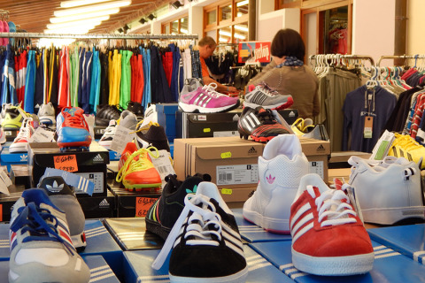 Scarpe sportive e abbigliamento colorato esposti in un negozio al Camping Pra'delle Torri, Veneto, Italia.