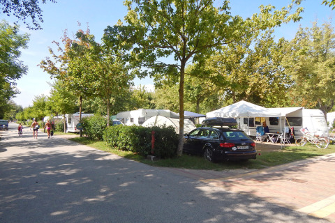 Campeggio con roulotte, auto e biciclette sotto gli alberi al Camping Pra’delle Torri, Veneto, Italia.